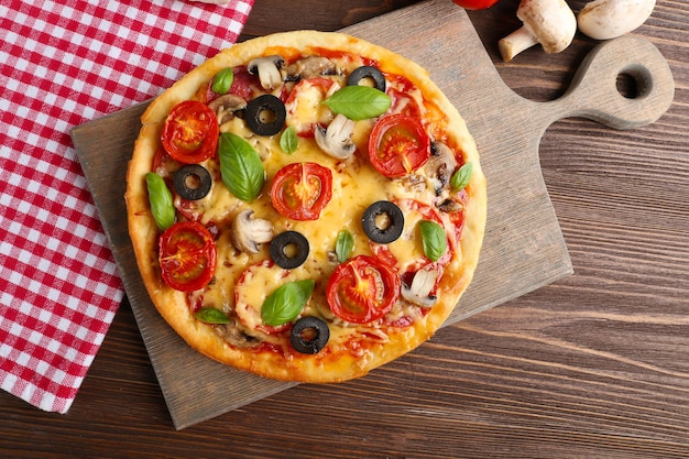Pizza saborosa com legumes e manjericão na mesa close-up