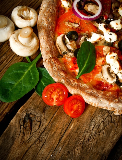 Pizza saborosa com tomates e verduras em uma placa de madeira.