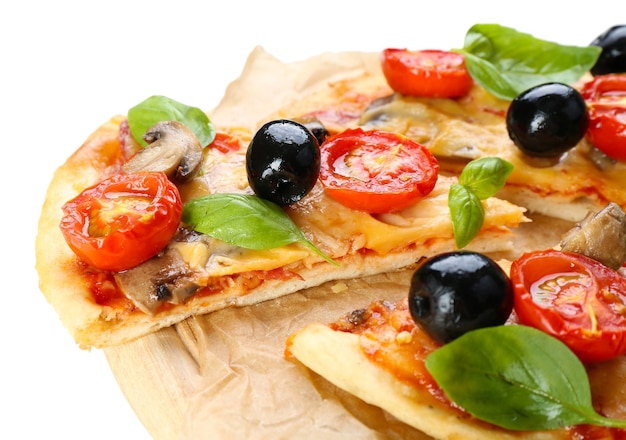 Pizza sabrosa con verduras y albahaca en la tabla de cortar de cerca