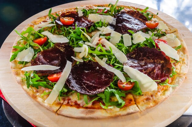 Pizza con salami y basturma, cebolla y albahaca