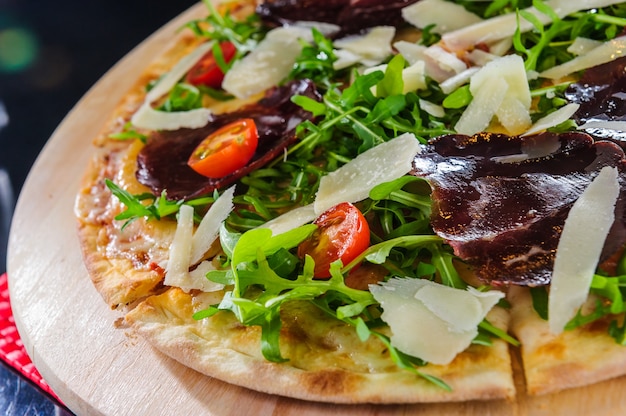 Pizza con salami y basturma, cebolla y albahaca