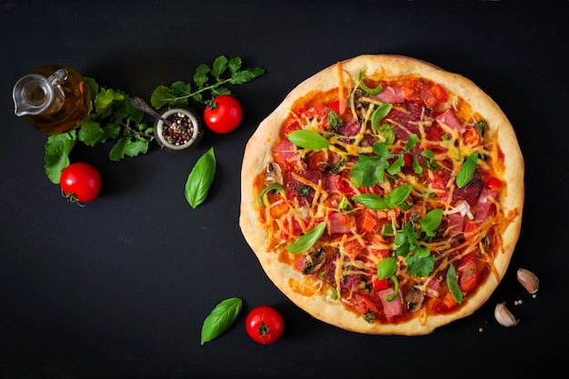 Pizza con salami, jamón, tomate, queso y champiñones