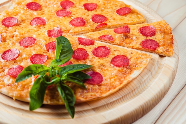 Pizza con salami en la mesa de madera