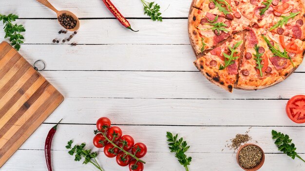 Foto pizza con salami de salchicha y mozzarella vista superior sobre un fondo de madera espacio de copia