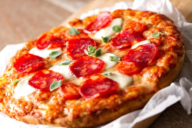 Pizza con salchicha de pepperoni y queso en una tabla de madera sobre un fondo de madera