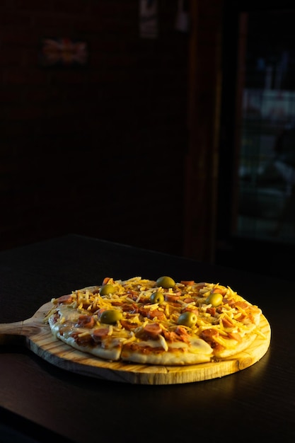 Foto pizza con salchichas y patatas sobre fondo negro