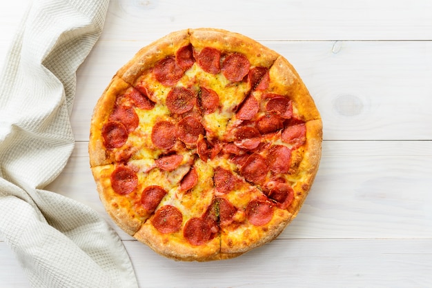 Pizza de salchichón en una mesa de madera clara. Orientación horizontal, vista superior, endecha plana.