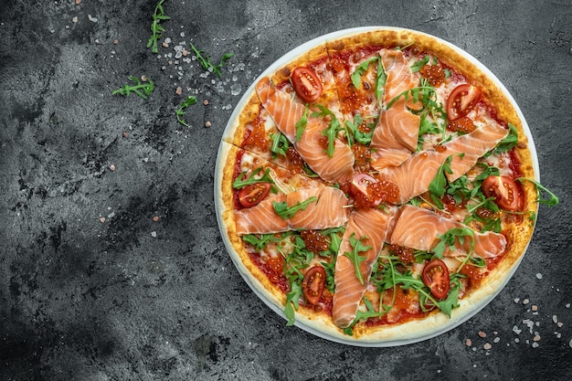 Pizza de salmón ahumado, caviar rojo, tomate y aragula lista para comer. banner, menú, lugar de recetas para texto, vista superior