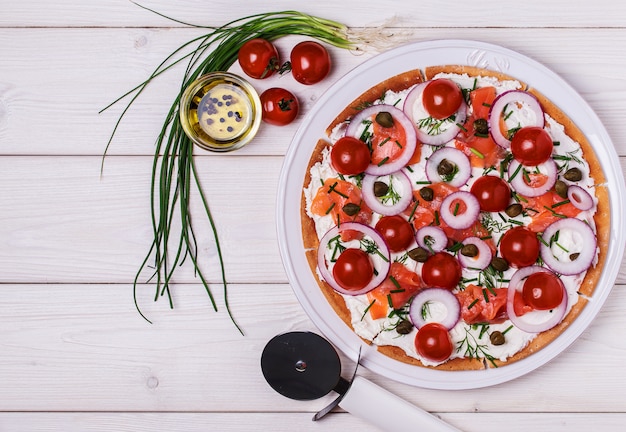 Pizza de salmón escandinavo con queso crema, tomate y cebolla.