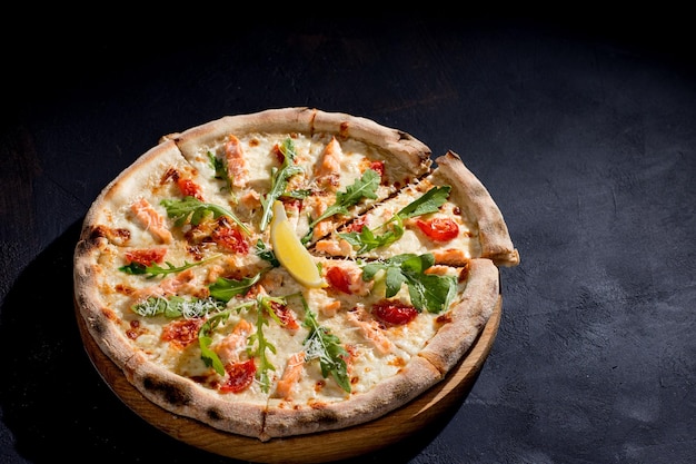 Pizza con salmón, mozzarella, tomates cherry, rúcula, limón y parmesano Cocina italiana Sobre un fondo negro Espacio libre para texto Vista desde arriba