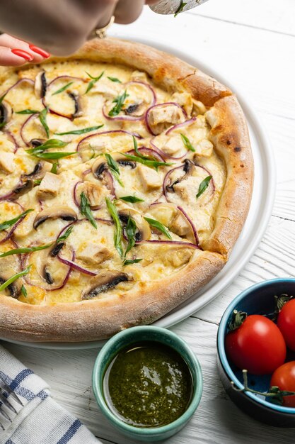 Una pizza con salsa roja y un plato de tomates