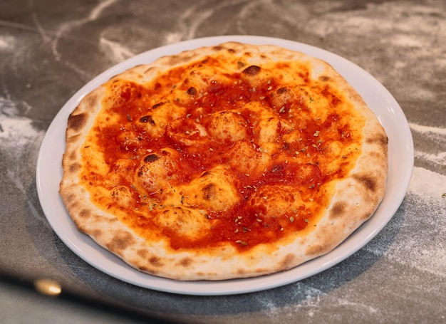 Una pizza con salsa roja se sienta en una mesa