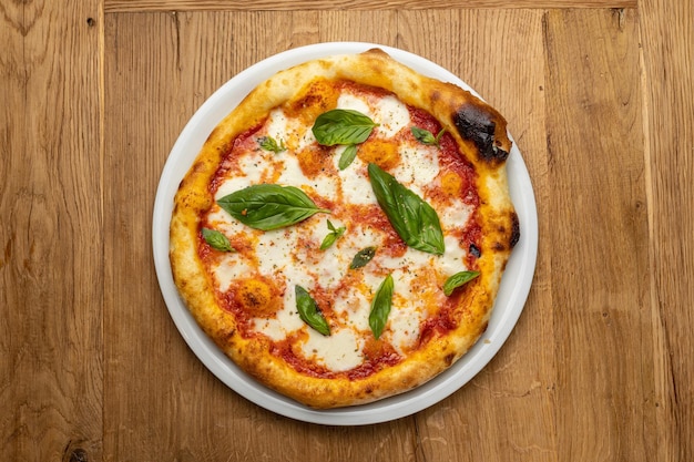 Una pizza con salsa de tomate y albahaca sobre una mesa de madera.