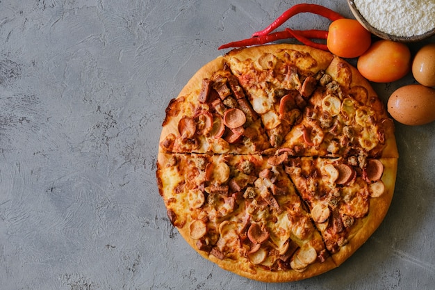 Pizza sobre fondo gris rústico, vista superior. Pizza con carne picada, apio y queso mozzarella de cerca.