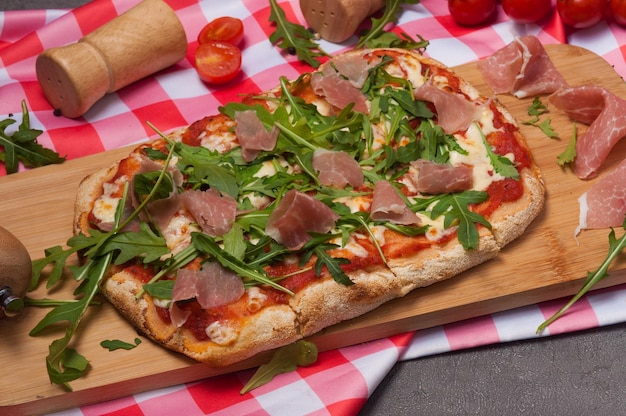 Pizza sobre masa romana con jamón y rúcula