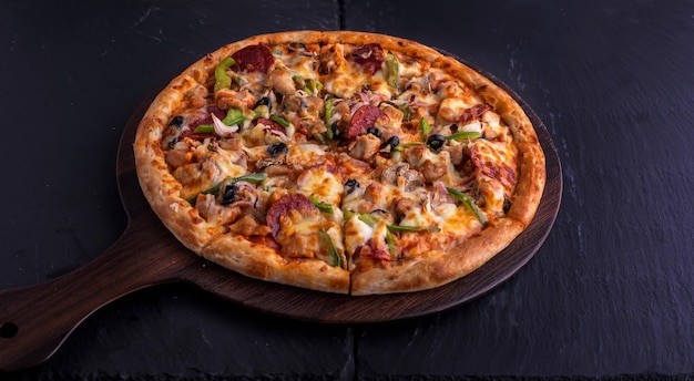 Pizza suprema de frango isolada na tábua de cortar vista superior em fast food italiano de fundo escuro