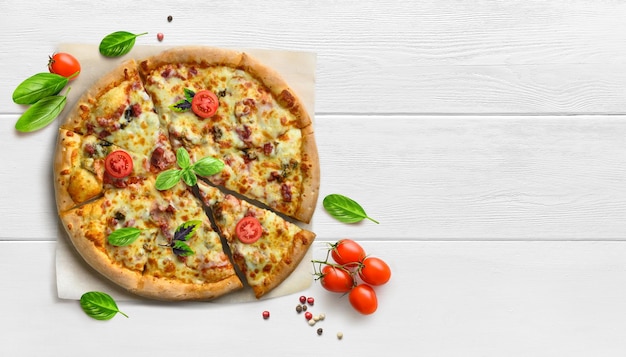 Pizza suprema quente na mesa de madeira branca com tomate e manjericão plano