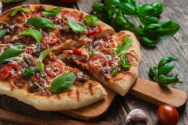 Pizza en una tabla de madera con albahaca y albahaca