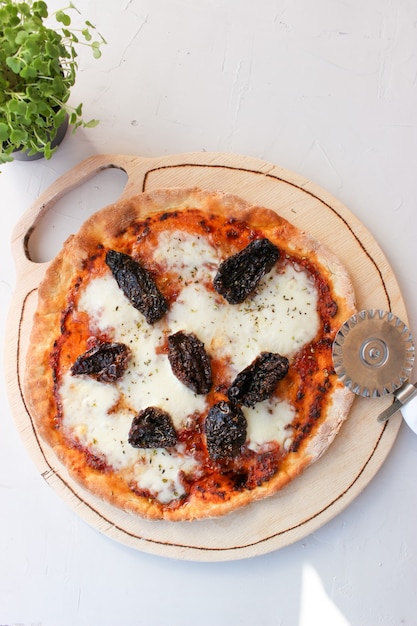 Pizza en una tabla de madera con mozzarella, mini rúcula.