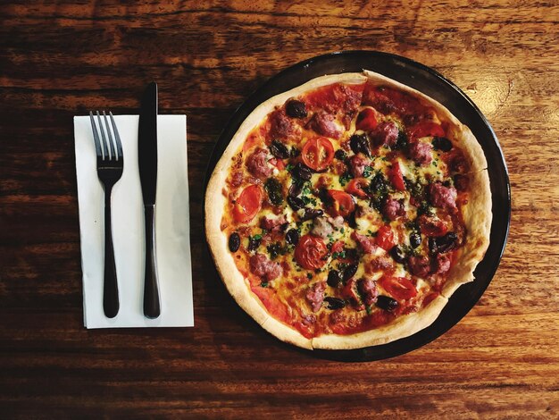 Foto pizza con tenedor y cuchara en una mesa de madera