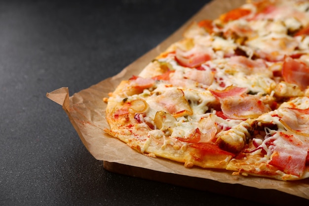 Pizza con tocino, verduras y salsa en la mesa de hormigón oscuro