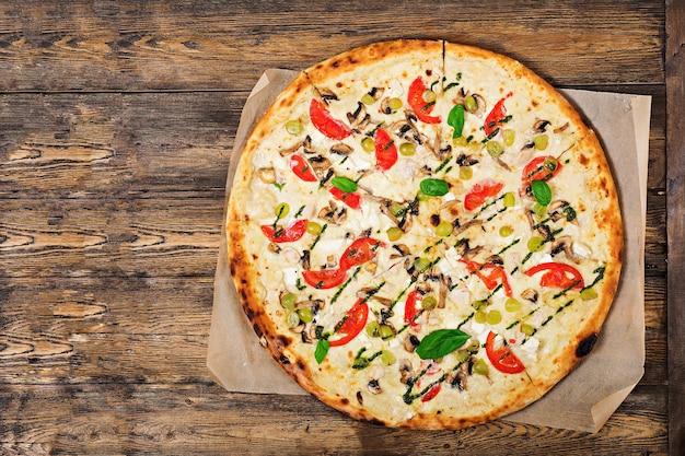 Pizza con tomate, mozzarella, champiñones y pesto de albahaca.