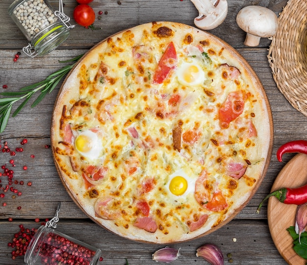 Pizza con tomate, queso mozzarella, aceitunas negras y albahaca