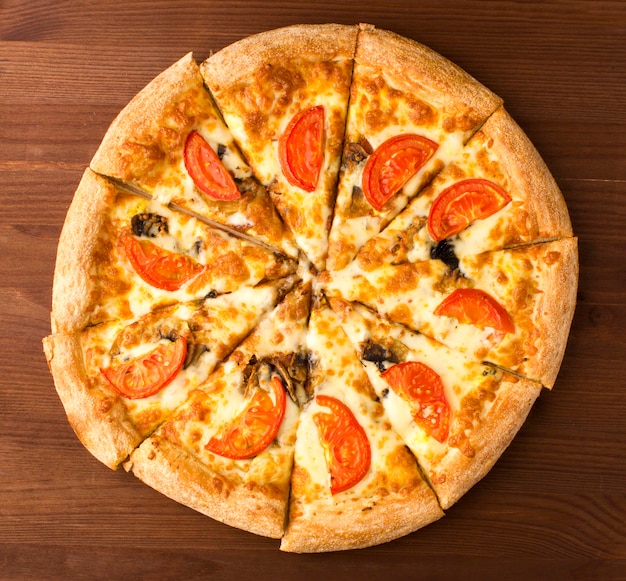 Una pizza con tomates y champiñones sobre un fondo de madera