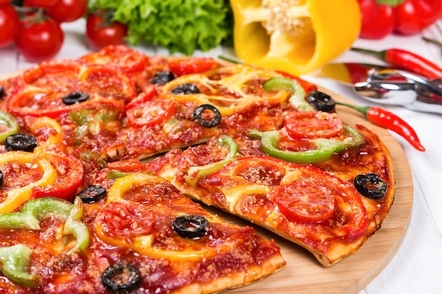 Pizza con tomates pimientos y aceitunas sobre un fondo de madera