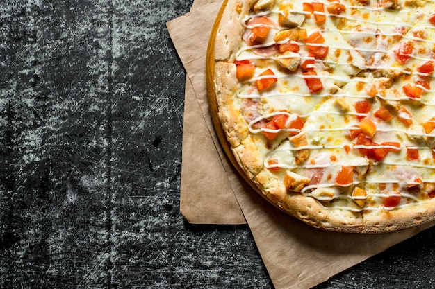 Pizza con tomates de pollo y salsa de queso en papel