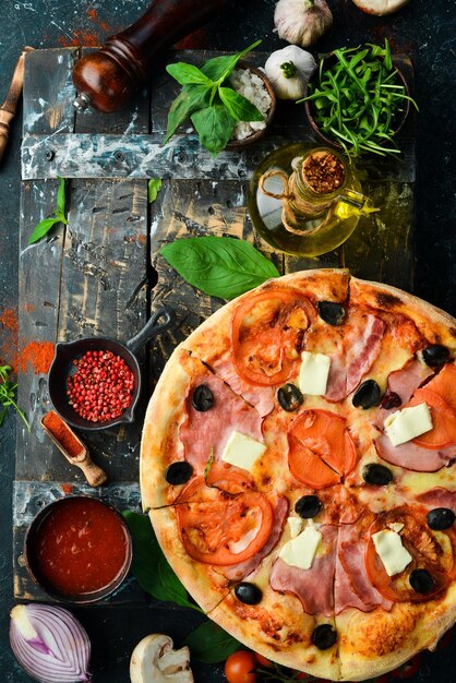 Pizza tradicional com bacon, tomate e queijo Em um fundo de pedra preta Espaço livre para texto
