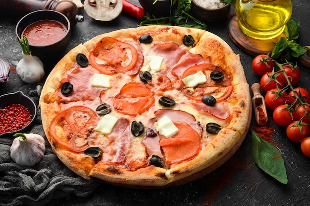 Pizza tradicional con tocino, tomates y queso Sobre un fondo de piedra negra Espacio libre para texto