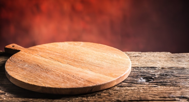Pizza vazia mesa de madeira velha de tábua redonda e cor de fundo desfocado.
