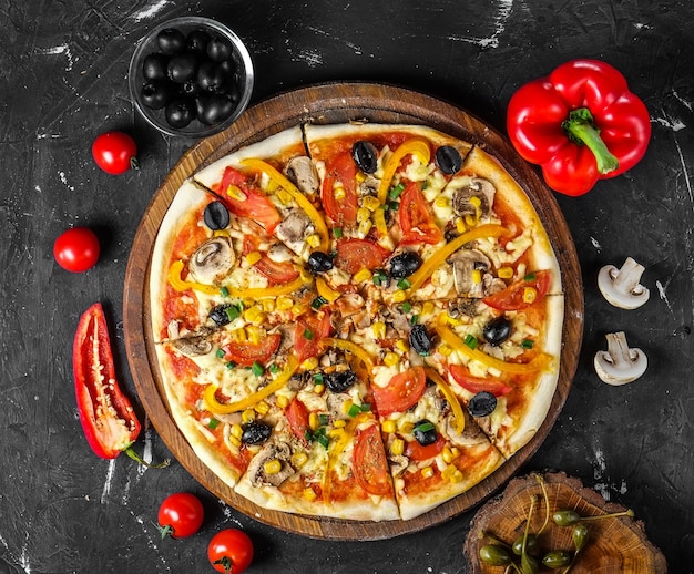 Pizza vegetariana con aceitunas, champiñones, maíz, rodajas de tomate, queso y cebollas verdes sobre una tabla de madera