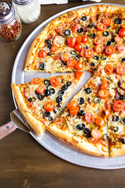 Pizza vegetariana com azeitonas e tomate cereja em cima da mesa.