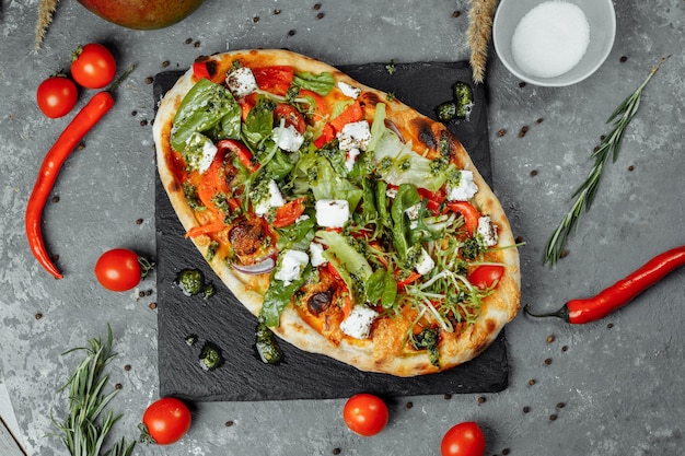 Pizza vegetariana com tomates e verdes de queijo.