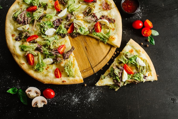 Una pizza vegetariana con verduras y hierbas sobre fondo negro