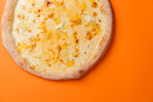 Pizza Vier Käse mit Mozzarella, Gouda, Camembert, Cheddar und Sahnesoße Orangefarbener Hintergrund, Ansicht von oben Kopieren Sie Platz