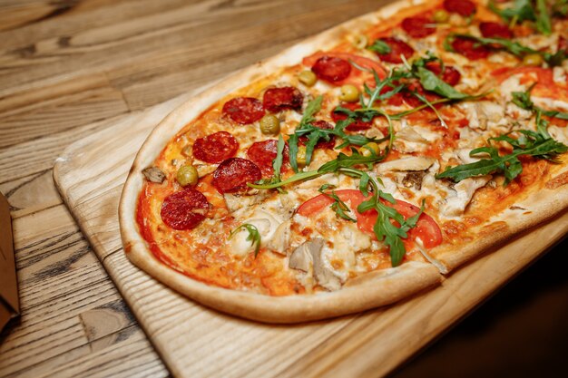 Pizza en la vista superior de la mesa de madera. Comida rápida.
