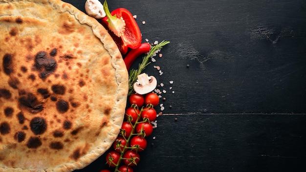 Pizza Volcano Gorgonzola-Käse Kirschtomaten frisches Gemüse und Gewürze auf einem hölzernen Hintergrund Freier Platz für Ihren Text Ansicht von oben