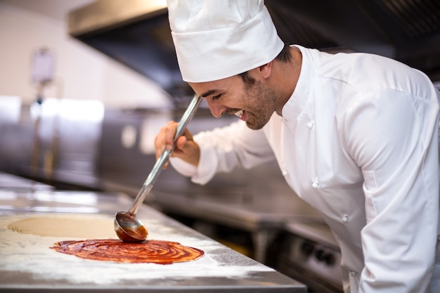 Pizzabäcker setzt Sauce auf Sockel