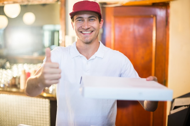 Pizzabote, der den Pizzakasten oben gestikuliert Daumen hält