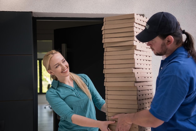 Pizzabote, der der lächelnden jungen Frau Pizzaschachteln gibt