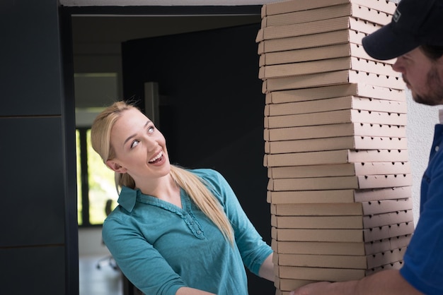 Pizzabote, der der lächelnden jungen Frau Pizzaschachteln gibt