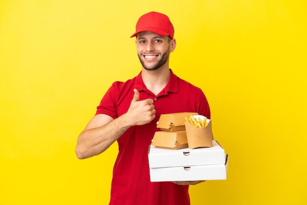Pizzabote, der Pizzakartons und Burger über isoliertem Hintergrund abholt und eine Geste mit dem Daumen nach oben gibt