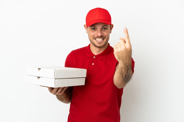 Pizzabote mit Arbeitsuniform, der Pizzakartons über isolierter weißer Wand aufhebt und kommende Geste macht