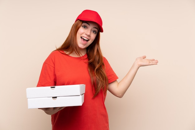 Pizzaboten-Teenager-Mädchen, das eine Pizza hält, die Hände zur Seite ausstreckt, um einzuladen, zu kommen
