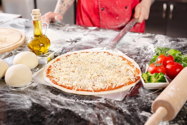 Foto pizzaiolo bereitet pizza in der küche zu, der koch bereitet den teig zu