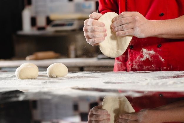 Pizzaiolo bereitet Pizza in der Küche zu, der Koch bereitet den Teig zu