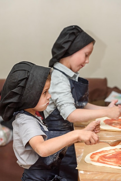 Pizzakinder und das Konzept des Kochens von Kindern machen Pizza